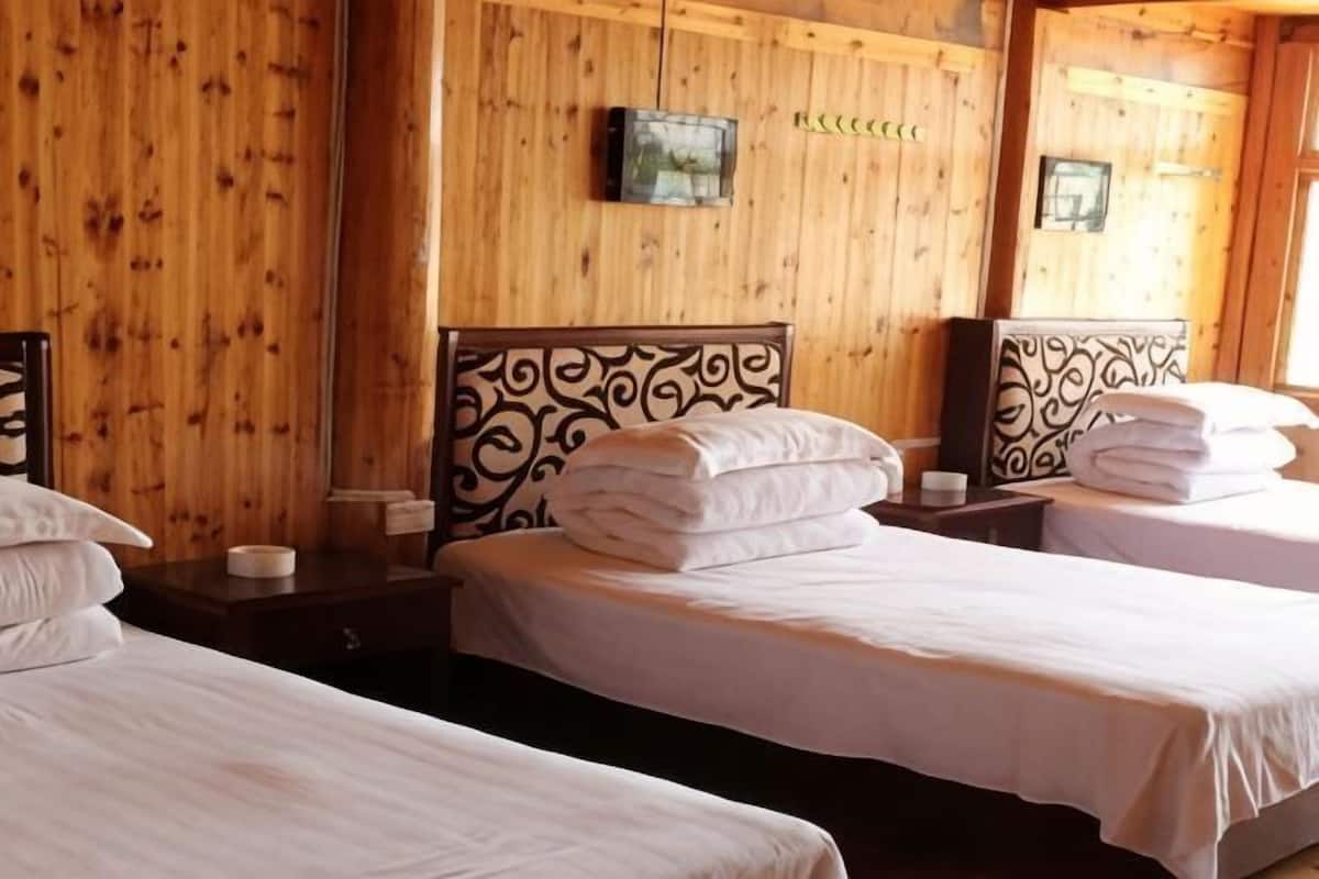 A hotel room with two beds, wooden walls, a television, and a framed picture.