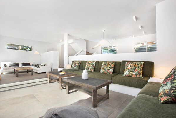 Una sala de estar moderna con un sofá, una mesa de centro y una escalera que sube a un nivel superior.