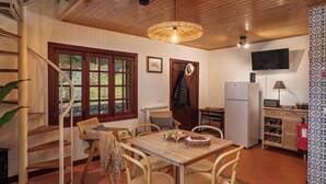Een houten interieur met een eettafel, stoelen, een trap, een keukenhoek en een televisie.