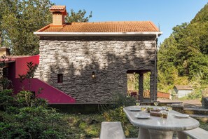 Set amidst lush surroundings, this charming abode offers a cozy dining area with a table and fruit.