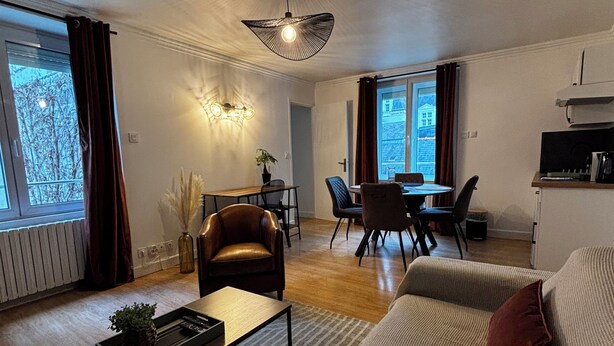 A modern living room with a sofa, coffee table, and a dining area with chairs and a table.