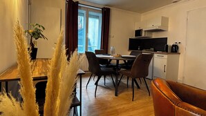 A modern kitchen with a microwave, stove, and cabinets. There is a dining area with a table and chairs, and a large window with curtains.