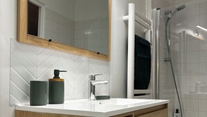 A modern bathroom with a wooden vanity, a large mirror, and a shower area.