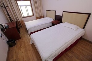A hotel room with two single beds, a wooden floor, a desk with a chair, and a window with curtains. - Lianyungang Military Music Hotel (Lianyungang High-speed Railway Station Square Store) (Lianyungang)