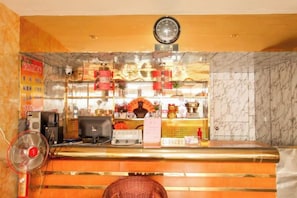 A reception desk with a clock, a fan, and a computer. - Lianyungang Military Music Hotel (Lianyungang High-speed Railway Station Square Store) (Lianyungang)
