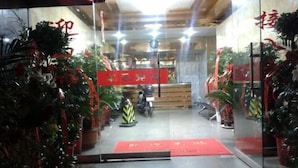 Un espace d’accueil avec un tapis rouge, des plantes en pot et une moto.