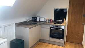 A compact kitchen with a built-in oven, a coffee maker, and a small trash bin. - Modern ensuite Studio Retreat off Vibrant Mill Rd (Cambridge)