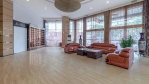 A spacious lobby with leather sofas, a coffee table, and a large chandelier. - Tuk China Light Residence Hotel (Taizhou Luqiao Airport Branch) (Taizhou)