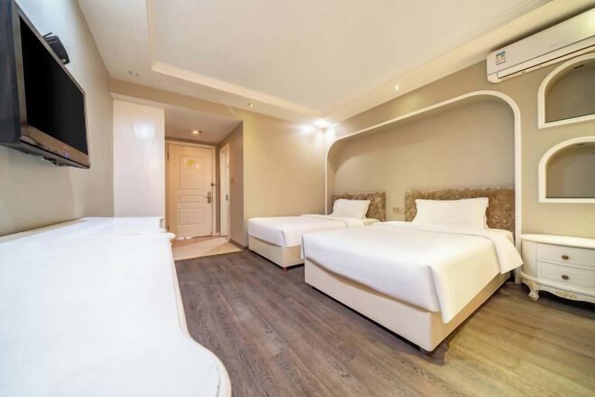 A hotel room with two beds, a TV, and a wardrobe.