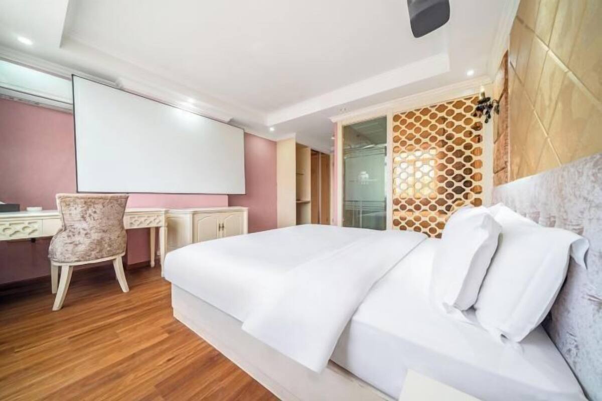 A bedroom with a bed, a desk, a chair, and a decorative wall panel.