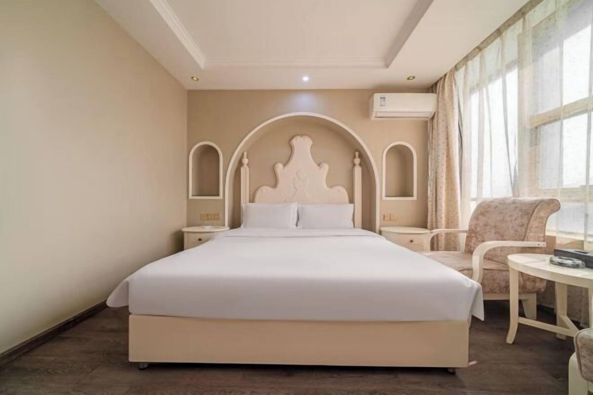 A hotel room with a large bed, two bedside tables, a chair, and a small table.