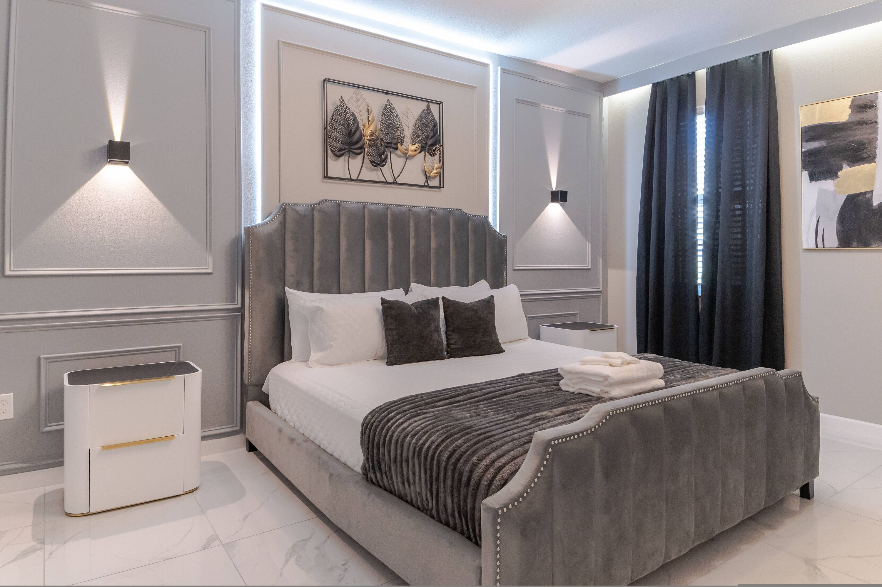 Un dormitorio moderno con una cama grande, mesitas de noche e iluminación integrada en la pared.