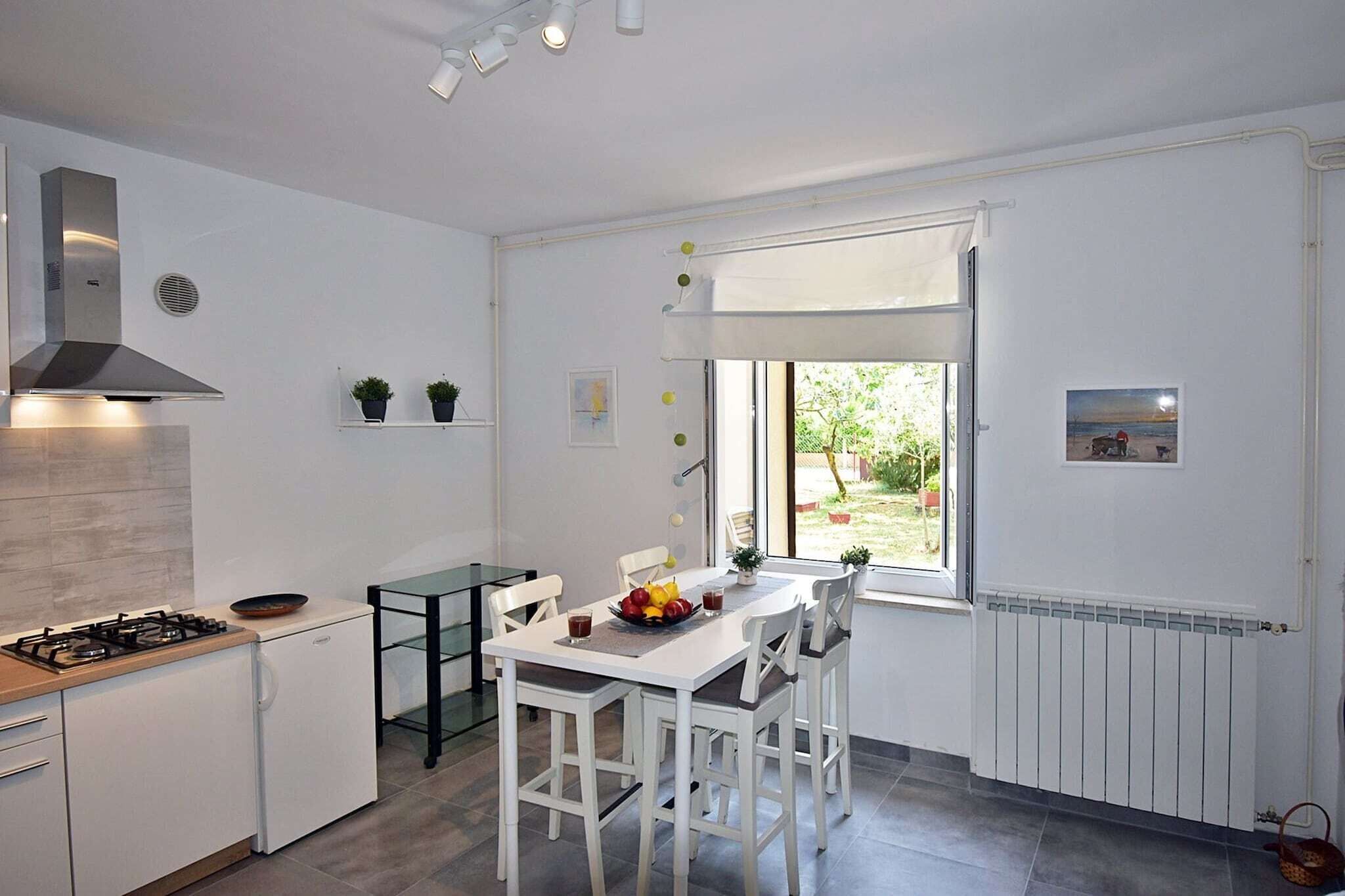 Een moderne keuken met witte kasten, een gasfornuis en een eethoek met een tafel en stoelen.