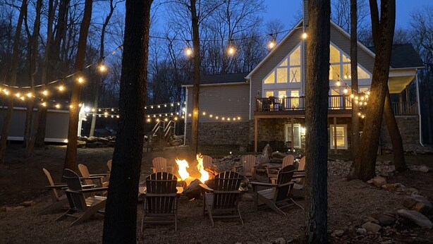 A house with a stone exterior, a fire pit, and outdoor seating. - Family Friendly Mountain Getaway with Theater & Arcade in the Laurel Highlands (Somerset)