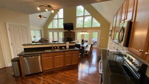 A spacious kitchen with a large island, wooden cabinets, and a stone fireplace. - Family Friendly Mountain Getaway with Theater & Arcade in the Laurel Highlands (Somerset)