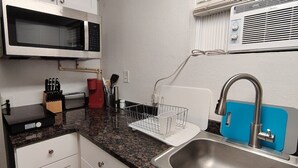 Een kleine keuken met een magnetron, broodrooster, spoelbak en messenblok.