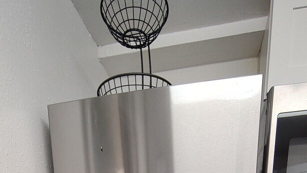 Een koelkast van roestvrij staal in een keuken met witte kasten en een magnetron erboven.