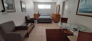 Ein gemütliches Schlafzimmer mit Bett, Schlafsofa, Glastisch und Kommode.