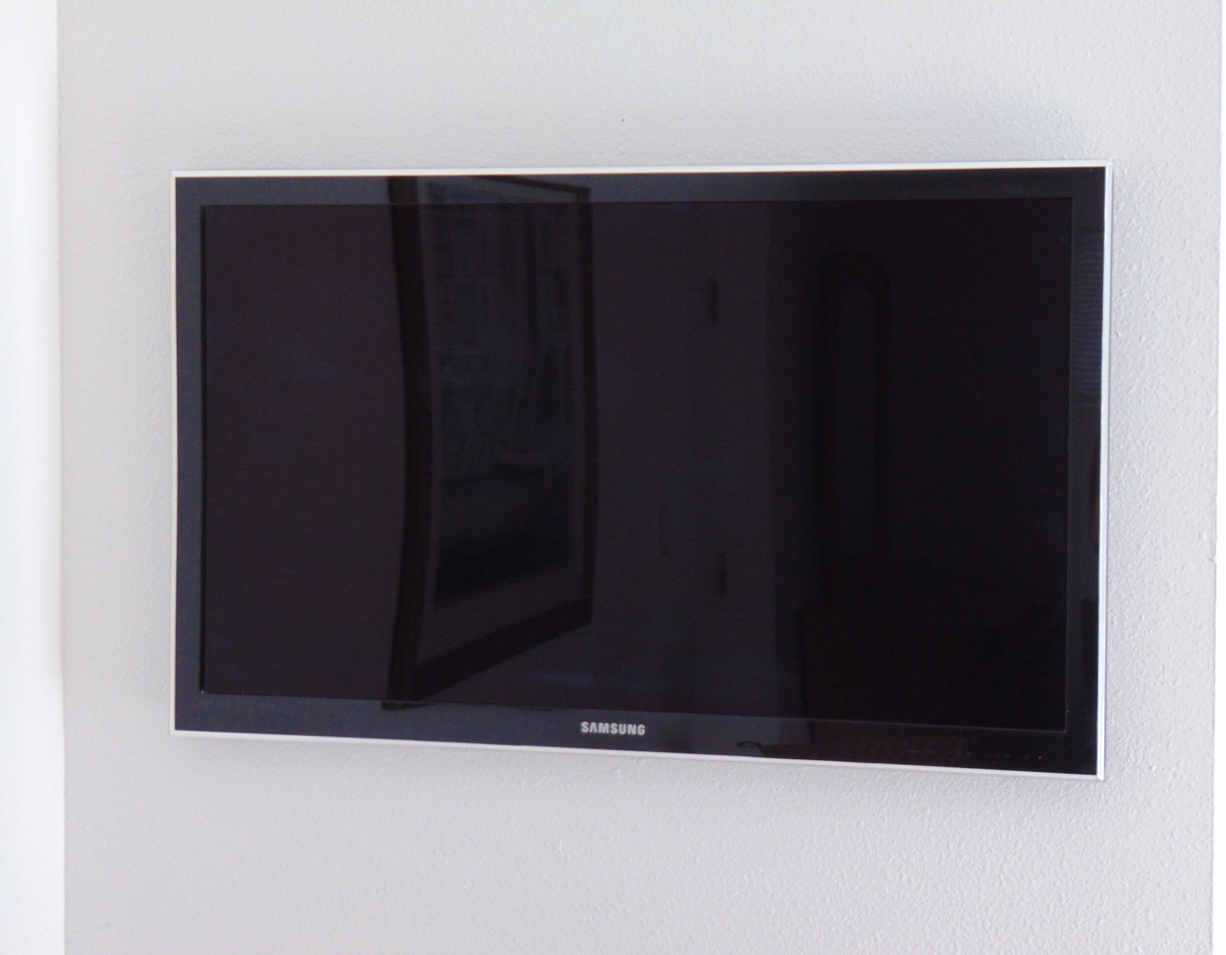 A Samsung flat-screen TV mounted on a white wall.