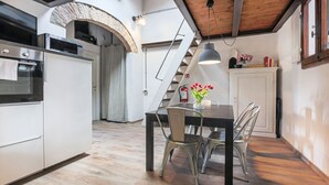 Een keuken met moderne apparaten, een eettafel met stoelen en een trap naar een ander niveau.