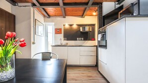Een moderne keuken met witte kasten, een zwart aanrecht en een houten plafond.