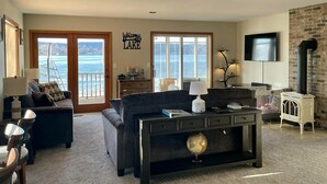 A living room with a sofa, a coffee table, and a TV. There is a fireplace and a view of the lake. - Waterfront Lake House with game room, private pier and kayaks in Lake Geneva (Lake Geneva)