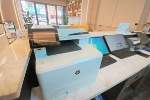 Een receptiebalie met meerdere HP-printers, een laptop en een desktopcomputer.