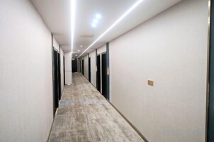 A long, narrow hallway with doors on both sides, a carpeted floor, and recessed lighting.