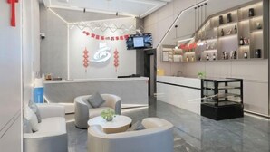 A modern hotel lobby with a reception desk, seating area, and a display of amenities.