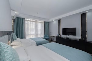 Una habitación de hotel con dos camas, televisión, escritorio y una silla.