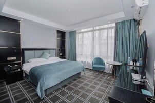 Una habitación de hotel con una cama grande, una mesita, una silla y un televisor.