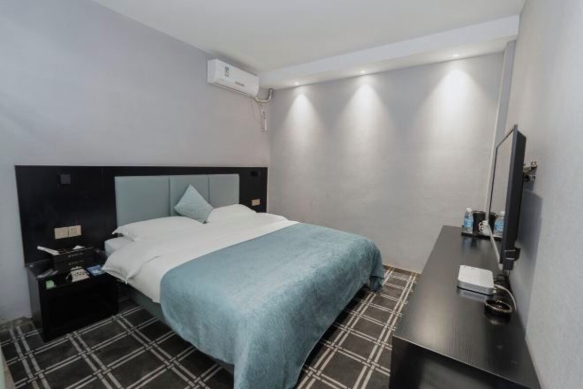 Une chambre d’hôtel comprenant un lit, une table de chevet avec une lampe, un miroir et un climatiseur fixé au mur.
