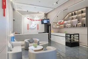 Een moderne hotel lobby met een receptiebalie, een zithoek en een bar.