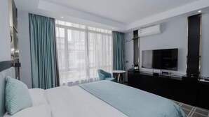A hotel room with a bed, a TV, a desk, and a chair.