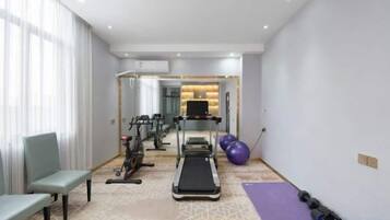 A fitness room with a treadmill, exercise bike, and free weights.