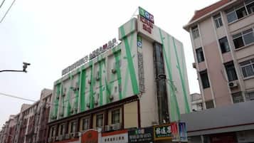 Um edifício com vários andares, com sinalização de hotel e diversos estabelecimentos comerciais no térreo.