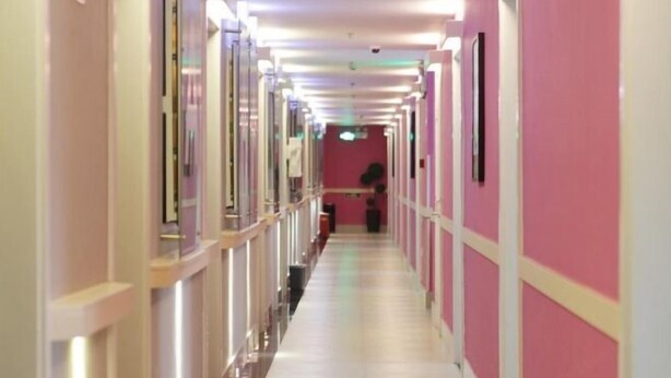 A long, narrow hallway with a pink and white color scheme, featuring a series of doors on one side and a trash bin on the other. - 100 Inn (Small Shanghai pedestrian street) (Shanghai)