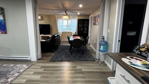 A modern kitchen with a dining area, wooden flooring, and a water dispenser. - Clementsvale Oasis: Rest, Recharge, and Explore. (Clementsvale)