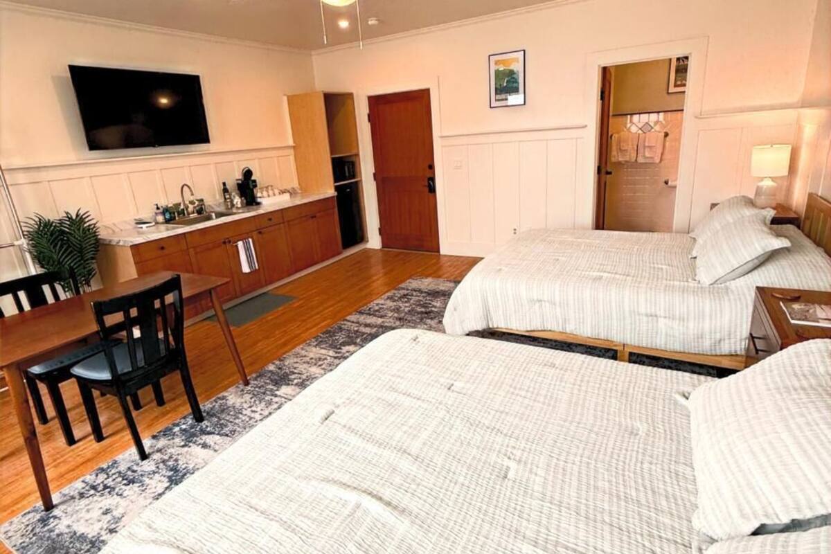 A bedroom with two beds, a desk, and a TV.