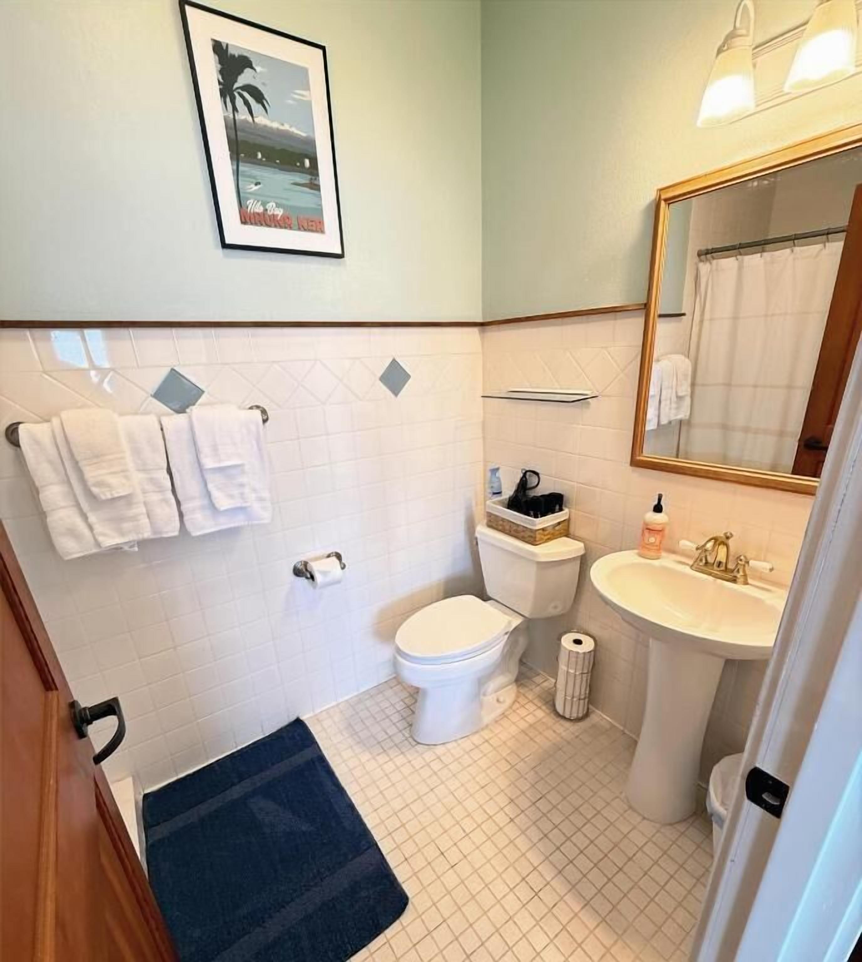 A bathroom with a toilet, sink, and a mirror.