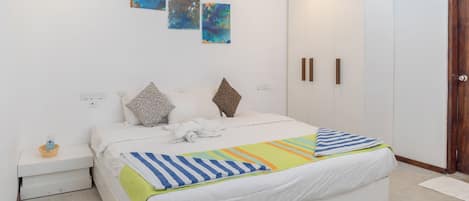 Un dormitorio moderno con una cama grande, paredes blancas y arte abstracto.