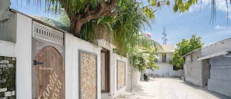 A narrow street with a white building featuring a wooden door with the text "Cardo" and a stone panel.