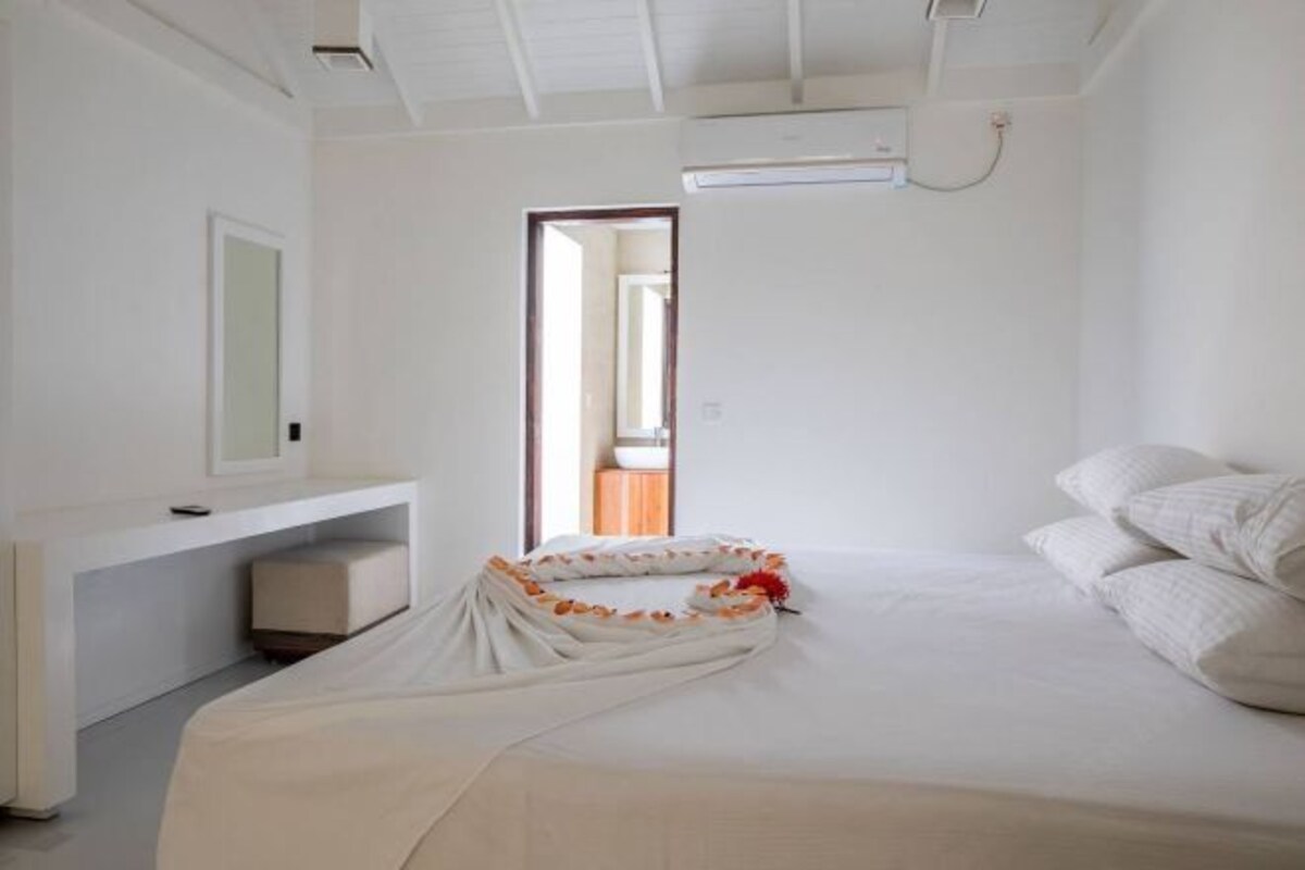 Un dormitorio con una cama, una mesita de noche, un espejo y una puerta que da a otra habitación.