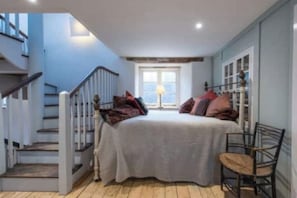 A bedroom with a bed, a chair, a window, and a staircase. - Enchanted Mill in Wiltshire (Bromham)