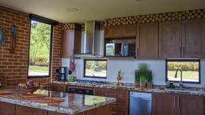 Una cocina moderna con una isla grande, electrodomésticos integrados y amplias ventanas que ofrecen vistas al exterior.
