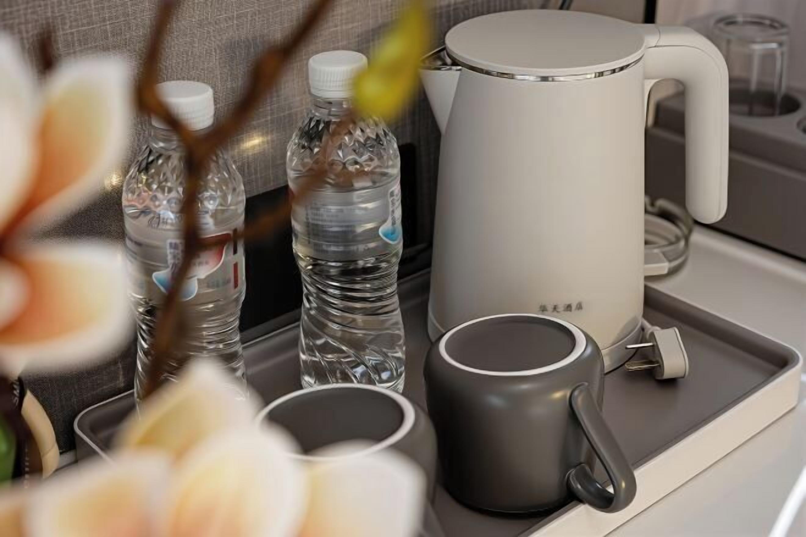 A tray with a water bottle, a mug, and a kettle on a table.