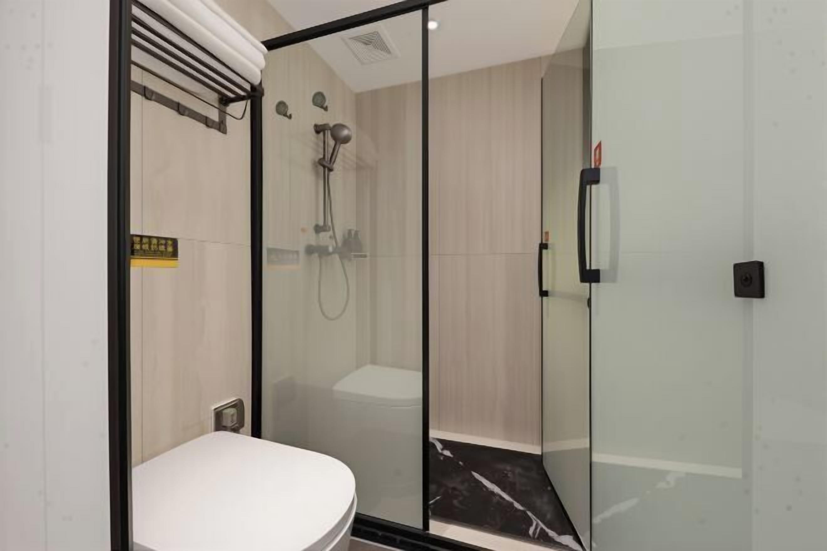 A modern bathroom with a glass shower enclosure, a toilet, and a visible control panel.