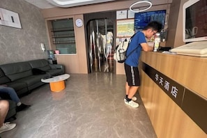 A hotel reception area with a reception desk, a sofa, and a coffee table. - Huatian Business Hotel (Shenzhen)