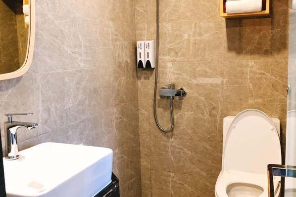 Un baño con lavamanos blanco, inodoro y zona de ducha.