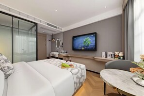 Camera d'albergo moderna con un letto, una scrivania, una televisione e vista sulla città.